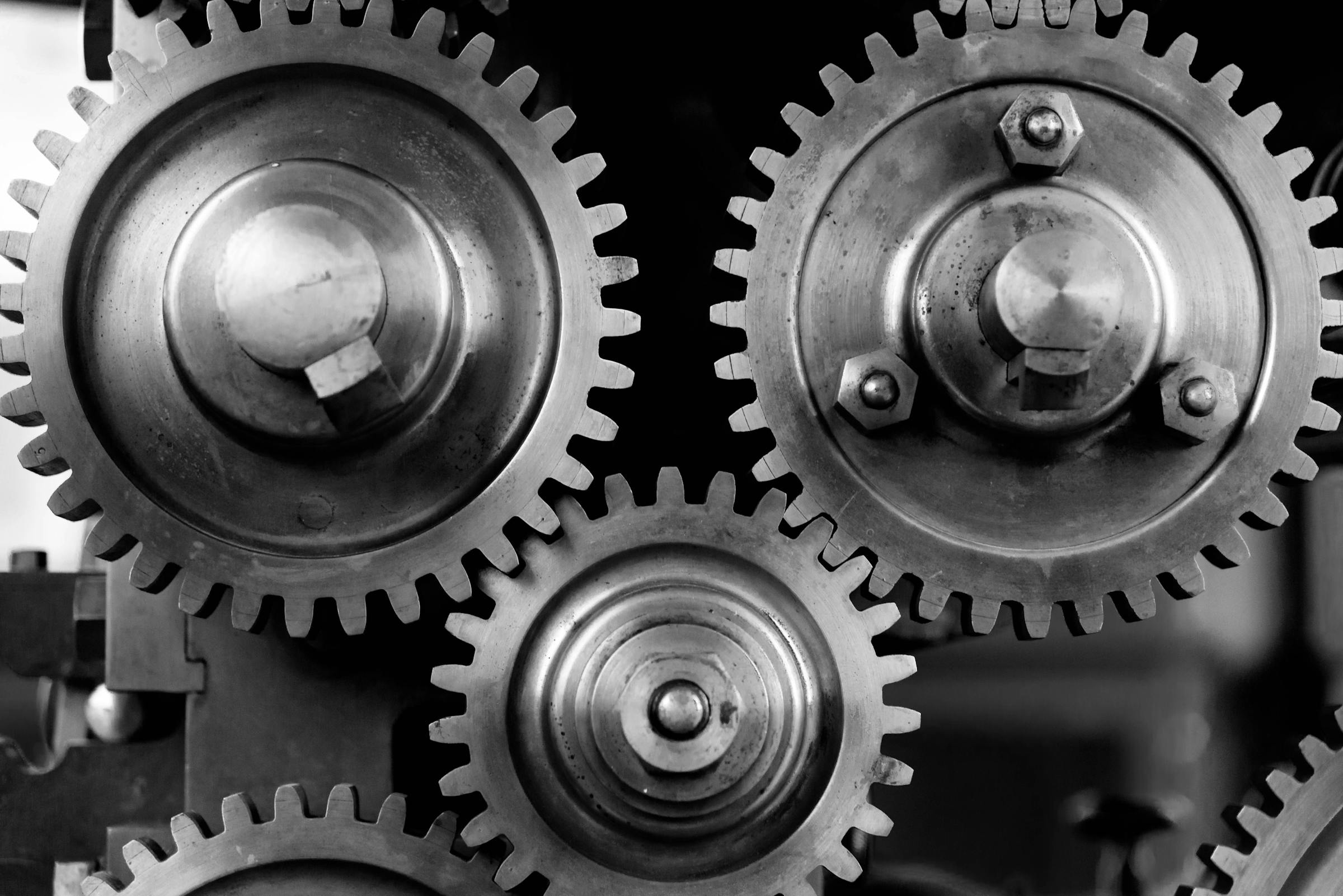 Schwarz-Weiß-Nahaufnahme verzahnter Metall-Zahnräder, Sinnbild für deterministische Mechanik klassischer Automatisierung gegenüber LLM-Black-Box