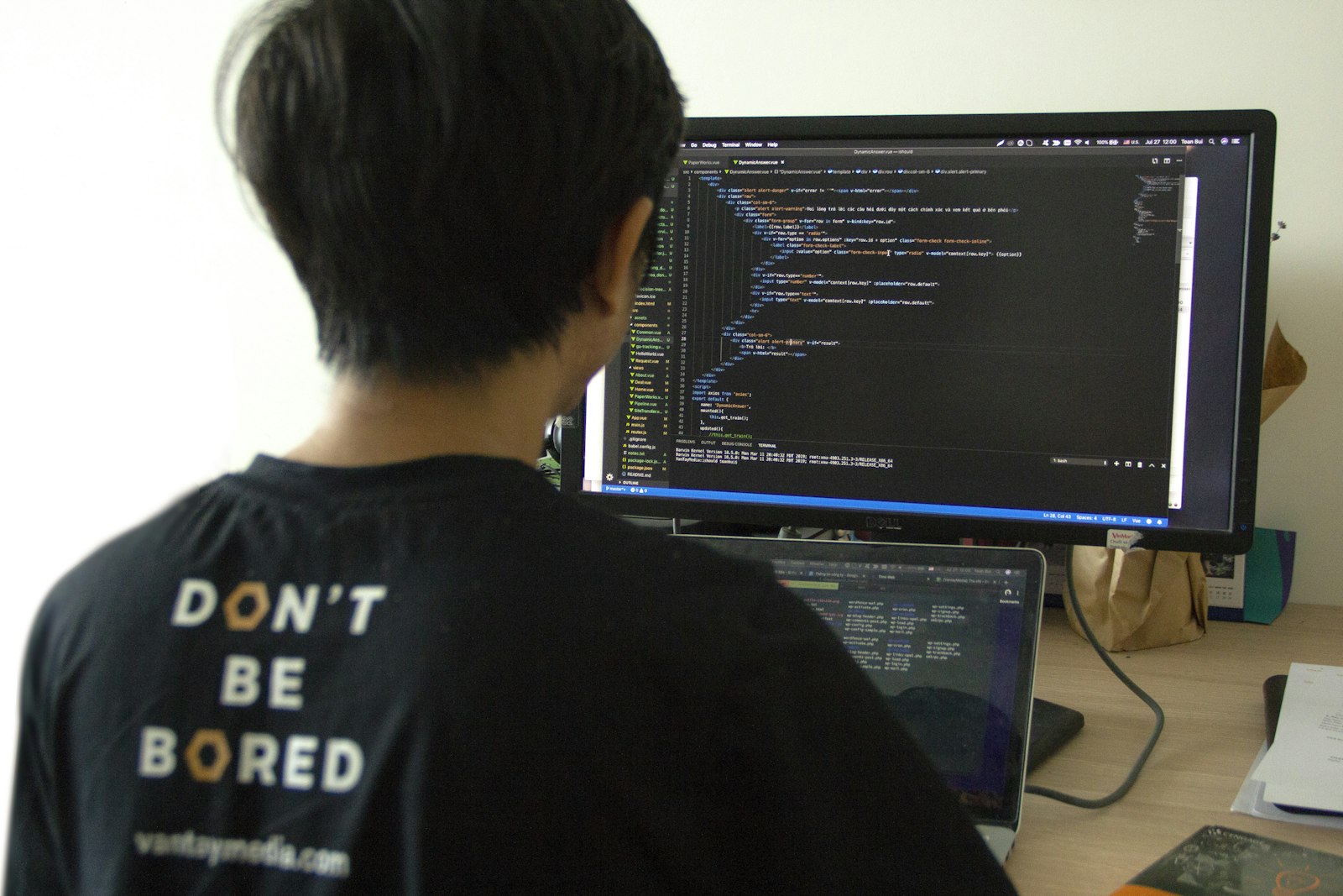 Entwickler arbeitet fokussiert an Code auf Laptop und externem Monitor, Debugging- und Reparaturarbeitsplatz